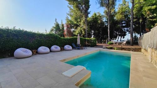 ein Swimmingpool mit weißen Kissen drumherum in der Unterkunft Velvet Pines Villa, Elani by Halkidiki Villas in Elani