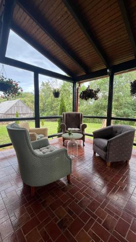 a living room with couches and chairs on a patio at Pensiunea Csató Borzont - Csató Panzió Borzont in Borzont