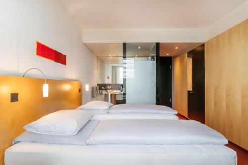 a row of four beds in a room at INNSiDE by Meliá Düsseldorf Seestern in Düsseldorf