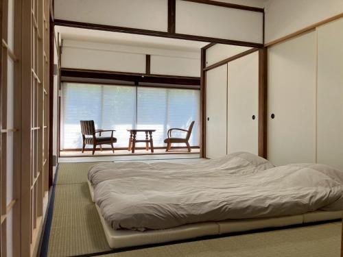 a bedroom with a bed and a table and chairs at 和宿520ゴーニマル緑青 in Kamakura