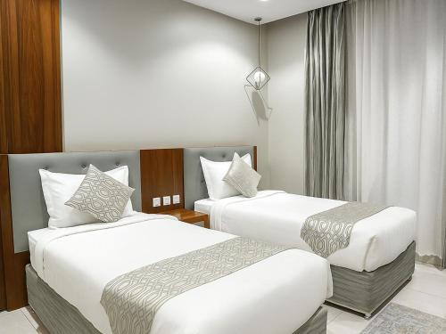 a hotel room with two beds and a window at Al Alamein Suites in Tabuk