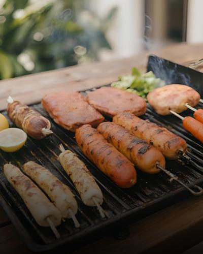 a grill with sausage and sausages and vegetables on it at Garden City Hotel Konjic in Konjic