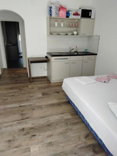 a room with a bed and a kitchen with wooden floors at Apartmani Sutomore Tri Palme in Sutomore