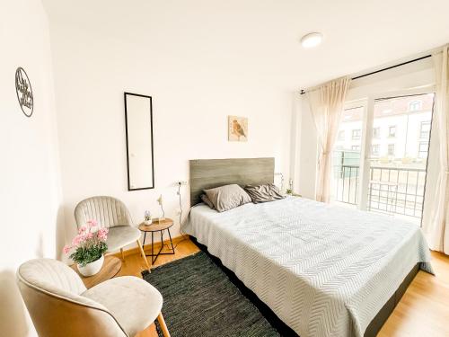 Un dormitorio blanco con una cama y una silla. en Apto MN Langosteira by ALÔGA, en Finisterre