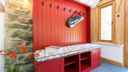 a red wall with a bench in a room at Ty Siam in Newborough