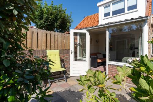 a patio with a white door and a yellow chair at Hello Zeeland - Vakantiewoning PJ Eloutstraat 13 in Domburg