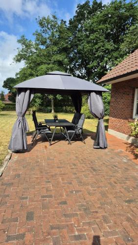 a table and chairs under an umbrella on a brick patio at Ferienwohnung Hof Segberg in Langenberg