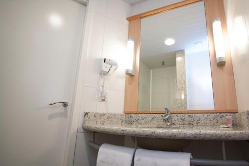 a bathroom with a sink and a mirror at ibis Cascavel in Cascavel