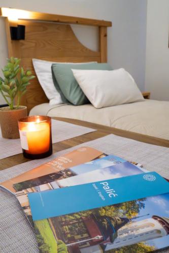 a table with a book and a candle next to a bed at Teatar Rooms Subotica 4 in Subotica