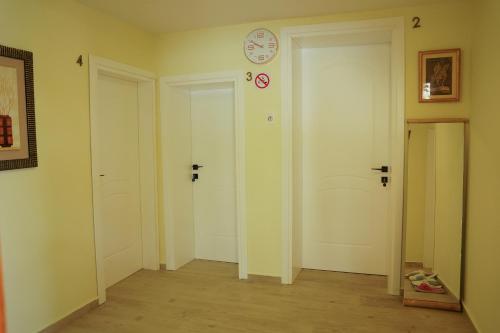 a room with two doors and a clock on the wall at Lemon House in Tirana
