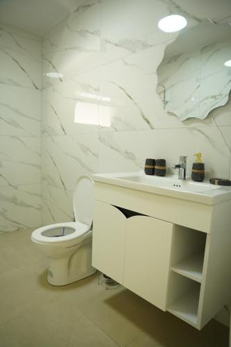 a white bathroom with a toilet and a sink at Lemon House in Tirana