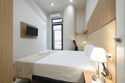 a bedroom with a white bed and a window at Apartamentos Constitución in Granada
