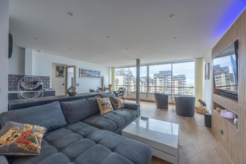 a living room with a couch and a large window at Le penthouse des ours in Courseulles-sur-Mer