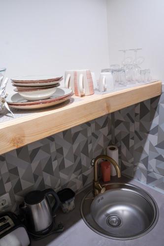 a kitchen sink with a counter with plates and dishes at Teatar Rooms Subotica 4 in Subotica