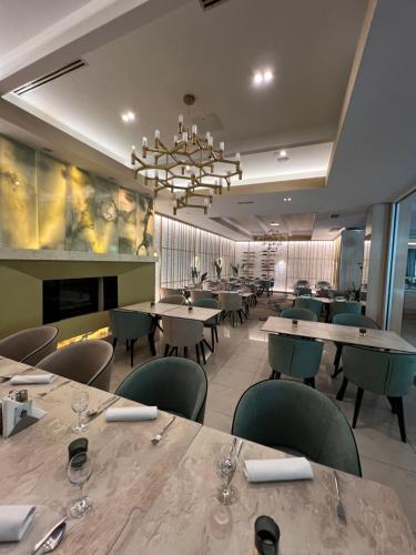 a restaurant with tables and chairs and a chandelier at Garden City Hotel Konjic in Konjic