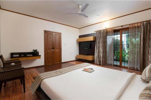 a bedroom with a large bed and a television at Dwaraka inn -Premium Pool villa and event venue in Coimbatore