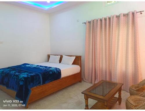 a bedroom with a bed and a table and curtains at namaste Adoroni Guest House , Manas National Park in Jyoti Gaon