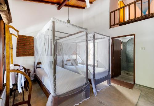 a bedroom with a four poster bed with mosquito nets at Lion's Rest in Weligama