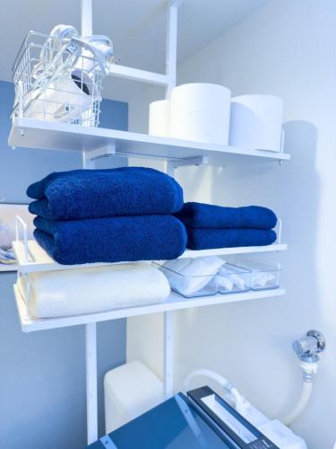 a group of towels on shelves in a room at つるのや鶴見105 in Yokohama