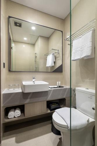 a bathroom with a sink and a toilet and a mirror at ROOMS INC Sudirman Jakarta in Jakarta