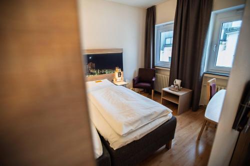 a hotel room with a bed and a chair at City Hotel Hannover in Hannover