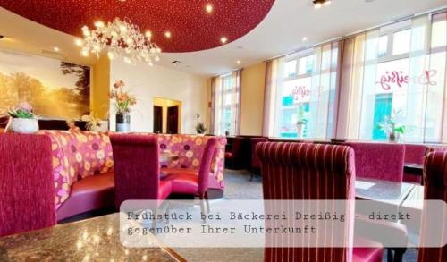 a restaurant with pink booths and a table and chairs at Der grüne Fürst Ferienwohnung Apartment 1 in Bad Muskau