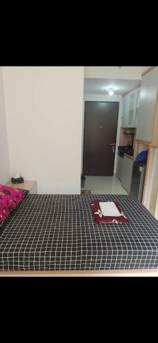a room with a bed with a checkered blanket on it at Apartemen Transpark by Lily's Room in Kalimanggis