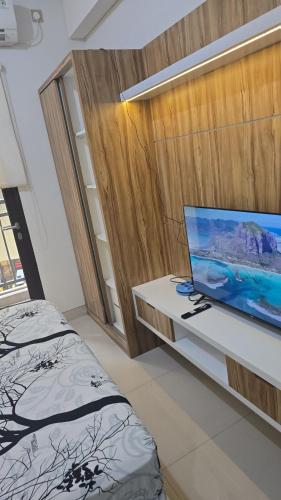 a bedroom with a bed and a desk with a tv at Apartemen Transpark by Lily's Room in Kalimanggis
