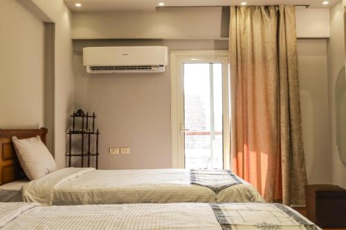 a bedroom with two beds and a window with a heater at المهندسين شقه سوبر لوكس - محى الدين ابو العز in Cairo