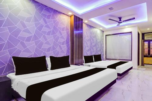 two beds in a room with a purple wall at Hotel O Priya Palace in New Delhi