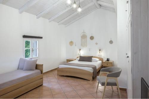 a white room with two beds and a chair at The Grove Seaside Hotel in Dhrepanon