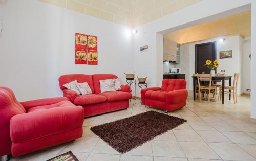 Una sala de estar con dos sofás rojos y una mesa. en Casa Libertà 32 by Quokka 360 - Among the alleys of Marsala, en Marsala