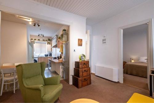 a living room with a green chair and a bedroom at City Cottage - Kalamata Villas in Kalamata