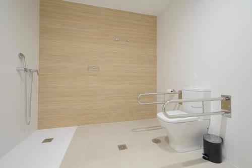 a bathroom with a toilet and a wooden wall at Apartamentos Constitución in Granada