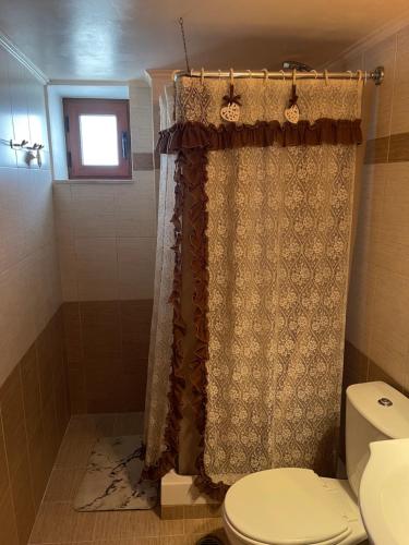 ein Bad mit einem Duschvorhang und einem WC in der Unterkunft Kamara Cottage - Traditional Stone House in Malona Village