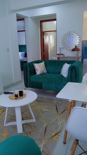 a living room with a green couch and tables at Tabbys staycation in Mombasa