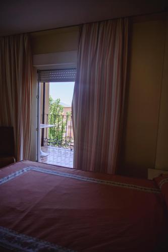 a bedroom with a window with a view of a balcony at Hotel Paraíso in Lanjarón