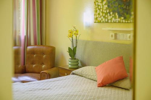 a bedroom with a bed and a chair and a vase with flowers at Hotel Paraíso in Lanjarón