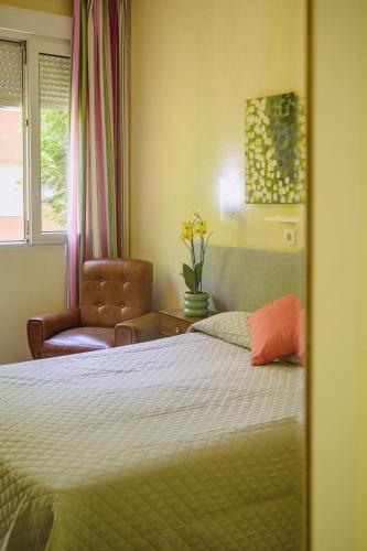a bedroom with a bed and a chair and a window at Hotel Paraíso in Lanjarón