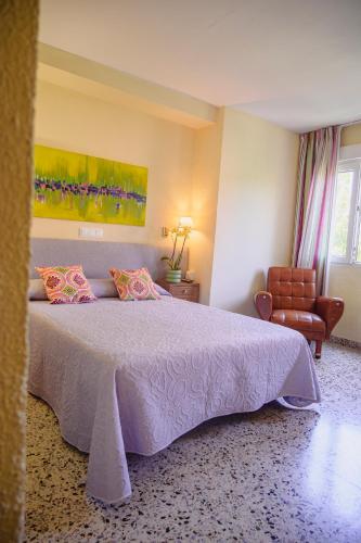 a bedroom with a large bed and a chair at Hotel Paraíso in Lanjarón