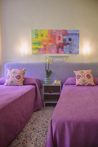 a purple room with two beds and a vase of flowers at Hotel Paraíso in Lanjarón