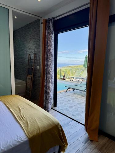 a bedroom with a sliding glass door with a view of the ocean at La Villa Des Oliviers chambres d hôtes in Petite Île