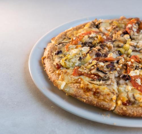 a pizza on a white plate on a table at Alkioni By The Sea in Siviri