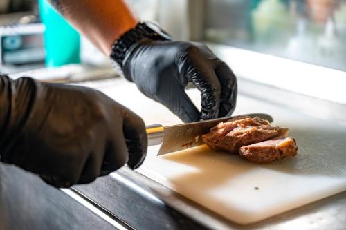 a person cutting a piece of meat with a knife at Alkioni By The Sea in Siviri