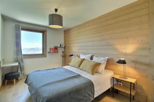 ein Schlafzimmer mit einem großen Bett mit einer Holzwand in der Unterkunft ARC 1600, LE RIDGE, Appartement 10 personnes Vue Montagne - ski aux pieds - Sauna, Hammam, Piscine in Arc 1600