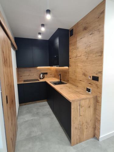 a kitchen with black cabinets and a wooden counter top at Apartamenty Nad Potokiem koło Karpacza in Staniszów