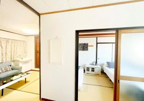 a living room with a bed and a glass door at Nippori Osaka Nishi-Tengachaya Guesthouse西天下茶屋アパートメント in Osaka