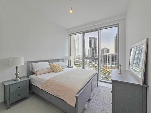a bedroom with a bed and a large window at Deluxe 1-Bedroom in The Grand - Waterfront and Skyline Views in Dubai