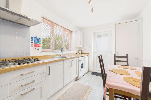 a kitchen with white cabinets and a table and a dining room at Host & Stay - Pier View in Amble