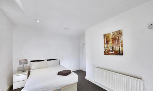 a white bedroom with a bed and a painting on the wall at No 4 AT MANNERING, LARGE 1 BED NEAR SEFTON PARK in Liverpool